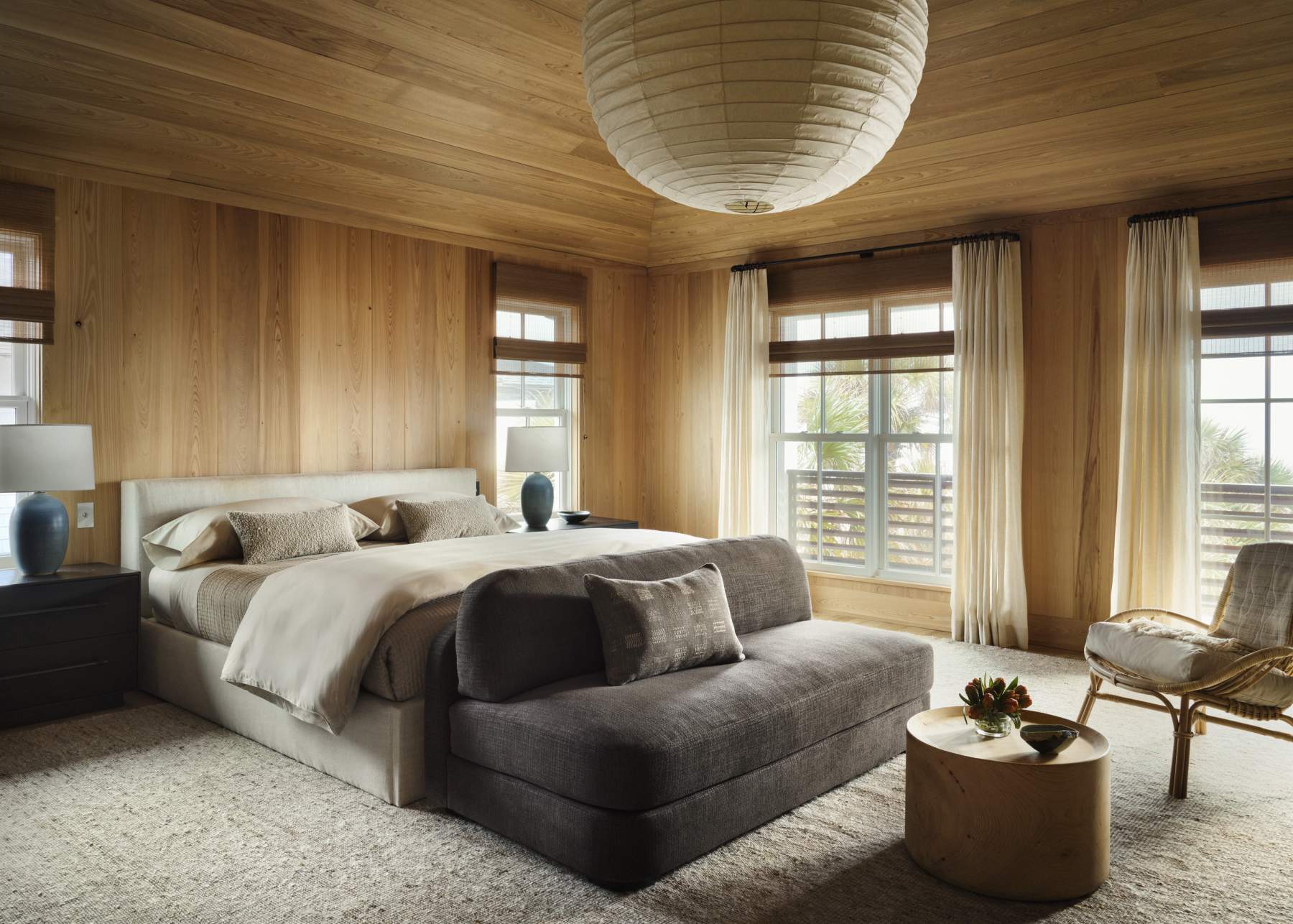 Wood-panelled bedroom with a paper lantern, a linen bed and a woven rug